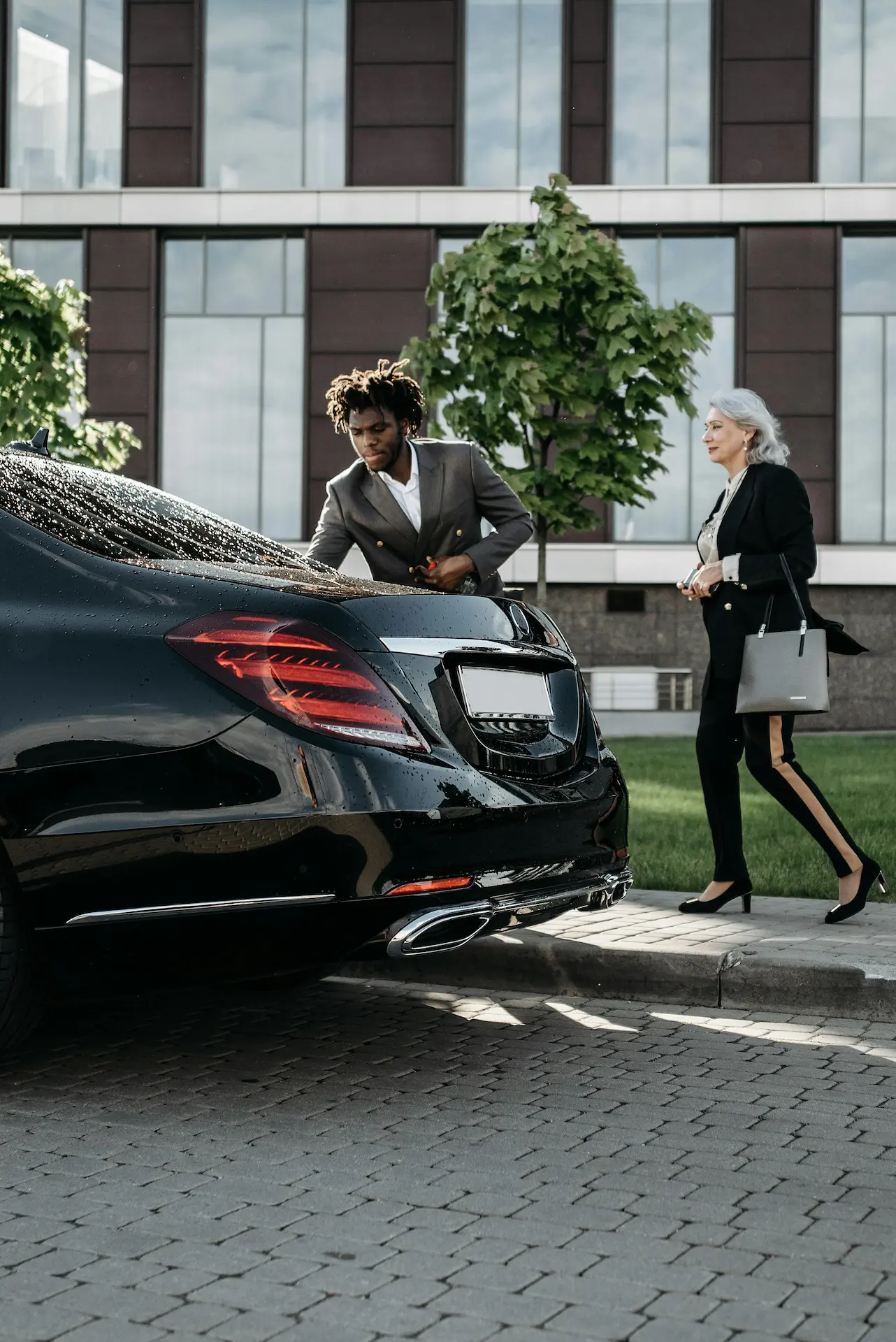 A chauffeur helping a business woman entering the car.